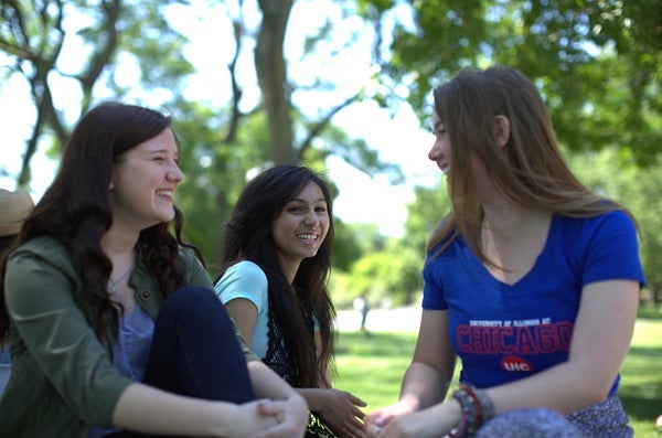 Group of students sitting on grass smiling and laughing